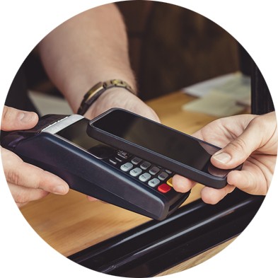 Mobile device held above payment processing machine at checkout.