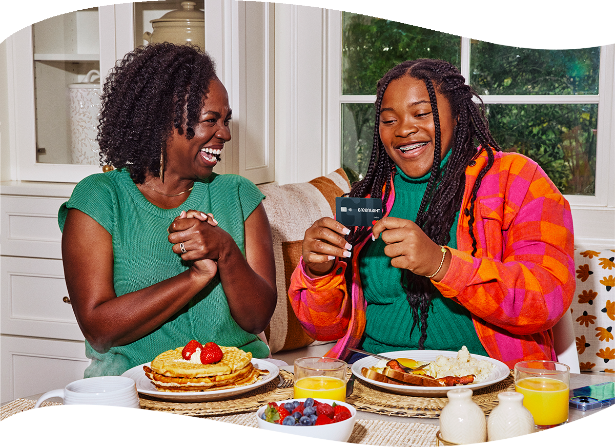 mother and daughter smiling at table with food holding a greenlight card